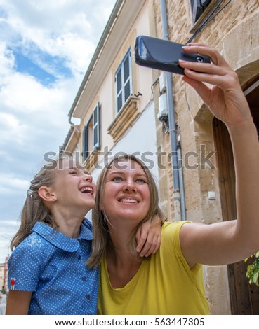 Mother and daughter taking selfie in old town.