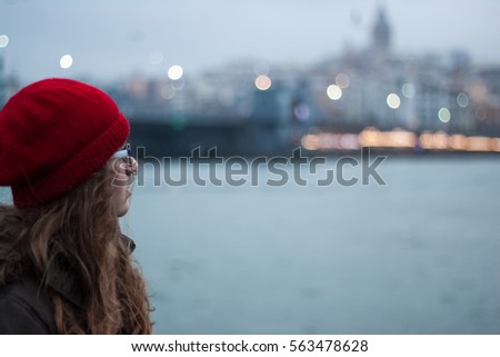 Beautiful cute little blonde girl with a red cap on his head was taken from the right side with a view of the lights of the great city