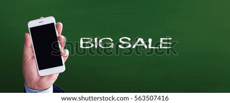 Smart phone in hand front of blackboard and written BIG SALE