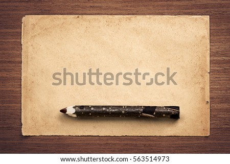 Old sheet of paper with eco pencil (made of branch) on wooden table.