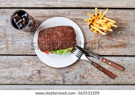 Rye bun burger and cutlery. French fries and cola drink. Junk food delicious recipe.