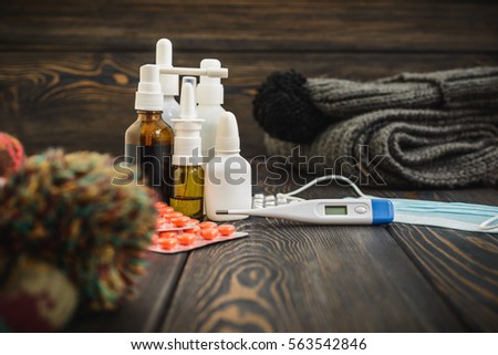 Medication tablets from illness and influenza on a rustic wooden background with woolen scarf and cap. thermometer with high temperature 39.1 per season