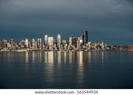 As the sun sets the buildings of the Seattle skyline are reflected in Elliott Bay.