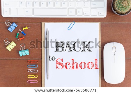 Text Back to school on white paper which has keyboard mouse pen and office equipment on wood background / business concept.