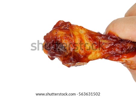 Spicy chicken leg on hand. Isolated on white background Royalty-Free Stock Photo #563631502