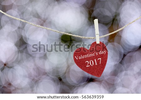 Red Heart hung on hemp rope and have text Happy Valentine's Day 2017 on abstract white color of boken background.