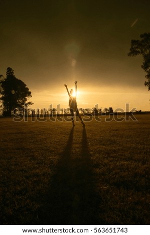 A woman rising arms in sunshine hour, sunset in a farm scene. Great image for freedom, meditation, peace usages
