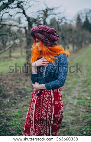 Redhead girl in the spring park in ethnic national dress with unusual makeup dancing with psychedelic trance music, yoga, esoterica, 