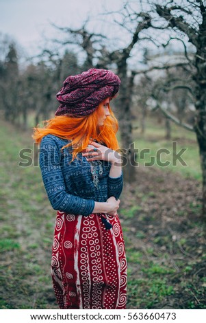 Redhead girl in the spring park in ethnic national dress with unusual makeup dancing with psychedelic trance music, yoga, esoterica, 