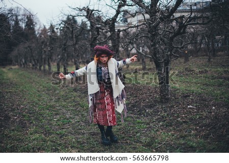 Redhead girl in the spring park in ethnic national dress with unusual makeup dancing to the psychedelic trance music, yoga, esoterica, caucasian lady looking like asian, saturated colors