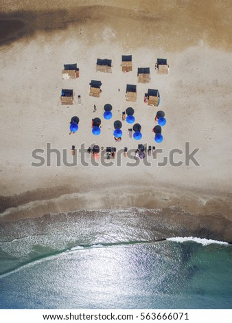 Tropical beach, sea and umbrellas with vacationers people. Taken from drone. Goa India - aerial view photo.
