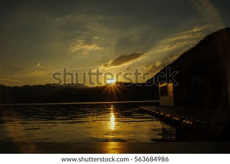 yellow sunset and mountain background and light reflect sunlight on lake and shadow of raft in Lake heaven resort, Kanchanaburi, Thailand