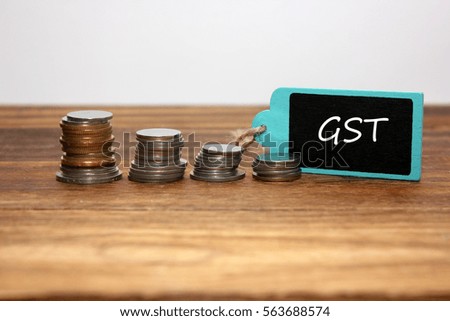 coins stacked and  gst written on the blackboard.