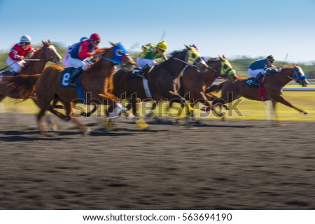Horse Race colorful bright sunlit slow shutter speed motion effect fast moving thoroughbreds Royalty-Free Stock Photo #563694190