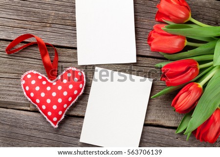 Red tulips bouquet, Valentines day heart and photo frames over wooden table. Top view with copy space 