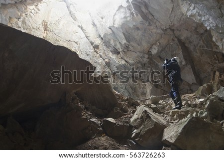 Caver in a helmet and with a lantern in the cave makes the output picture in the rays of light