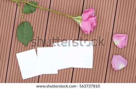 Empty notepaper with rose flower and petals on wooden.