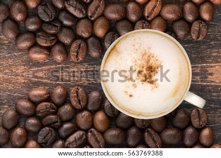 Cappuccino cinnamon topping on wooden table  and coffee beans. Cup of  cappuccino coffee top view