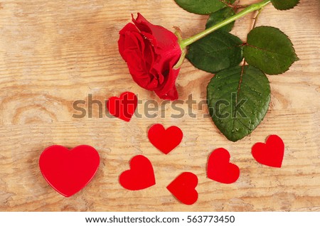 Red rose and red hearts on wooden table.