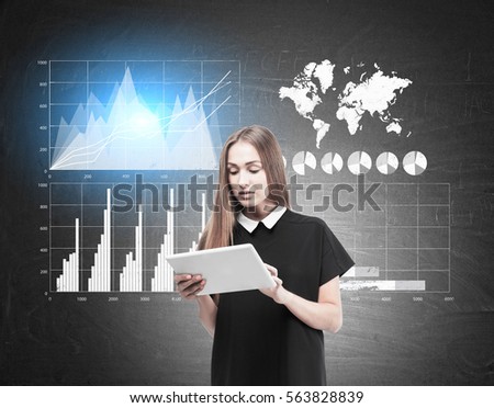 Portrait of a blond woman holding a white tablet computer and standing near a blackboard with four graphs. Toned image. Elements of this image furnished by NASA