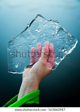 Young boy keeps in hand slice of ice floe in cold hand. Close up shot focus on ice.
