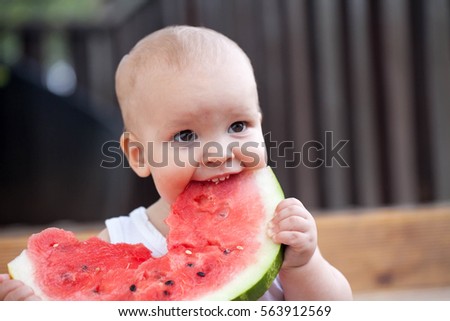 In the summer on the street on a wooden porch of a little boy eating watermelon red
