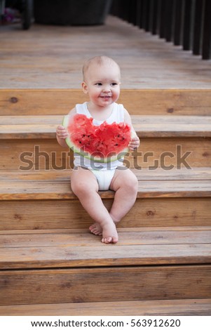 In the summer on the street on a wooden porch of a little boy eating watermelon red

