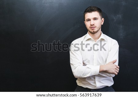 Portrait of confident office male with crossed arms isolated over black chalkboard