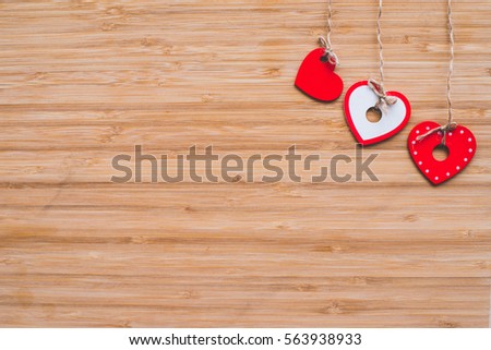 hanging red hearts on a wood texture with space for messages 