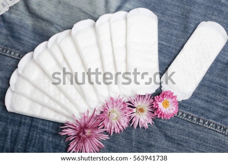 feminine pads with flowers on denim background