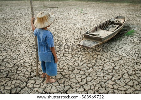 Global warming, Children with boat on cracked earth after the climate change  Royalty-Free Stock Photo #563969722