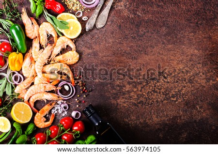 Fresh fish, shrimps with herbs, spices and vegetables on dark vintage background. Healthy food, diet or cooking concept. Free space for your background