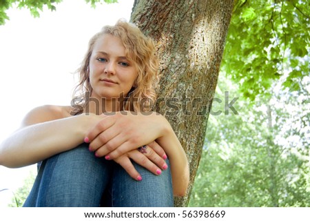 Portrait of young beautiful girl based on the park tree.