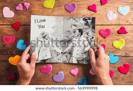Hands holding picture of senior couple, colorful hearts. Studio 