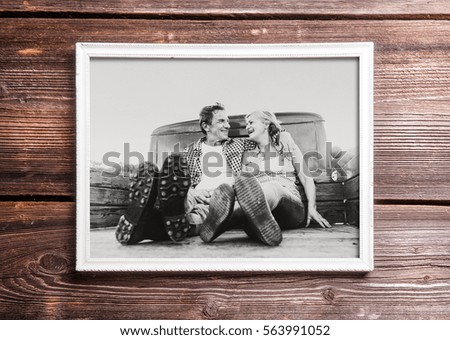 Photo of seniors in picture frame laid on wooden background.