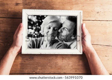 Hands holding black-and-white photo of senior couple in picture 