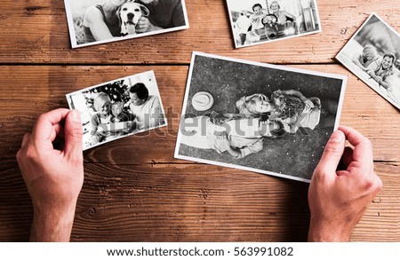 Hands holding various pictures of senior couple. Studio shot, wo