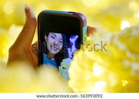 young adult asian girl take a selfie on beautiful yellow light background