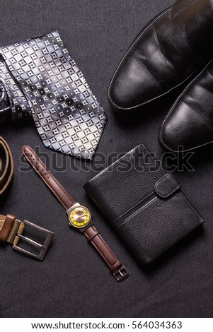 Men's accessories on black background tie wallet watch strap shoes