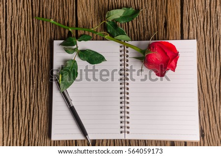 A photo of notepad  on old wooden background and red rose, Vintage concept Retro romantic styled