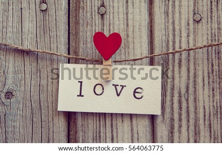 inscription love on white paper hanging on a rope with clothespin