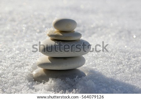 Harmony and balance, cairn, poise stones on light background, rock zen sculpture, five white pebbles, three pebbles in white snow, sunny