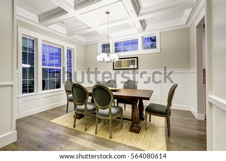 Lovely craftsman style dining room with coffered cealing over wooden dining table surrounded by grey chairs atop sisal rug. Northwest, USA
