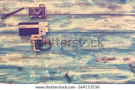 Video and photo cameras, audio cassettes, VHS video tapes on a blue old vintage background. Photographed in retro style. Old new concept