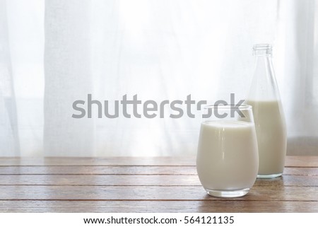 glass of milk on wooden table in the morning light