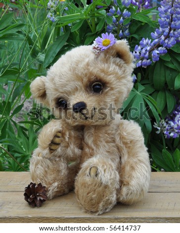 Handmade, the sewed toy: teddy-bear Lucky on a little board among flowers