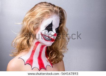 Portrait of a blond girl made up in joker with a fake smile in profile.
