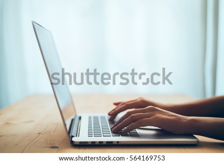 Woman hands typing on laptop keyboard at the office, Woman worker and business concept, Soft focus on vintage wooden table. Royalty-Free Stock Photo #564169753