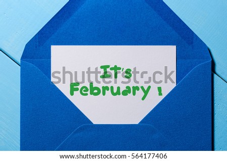 The text IT'S FEBRUARY written on a white paper in blue mail envelope