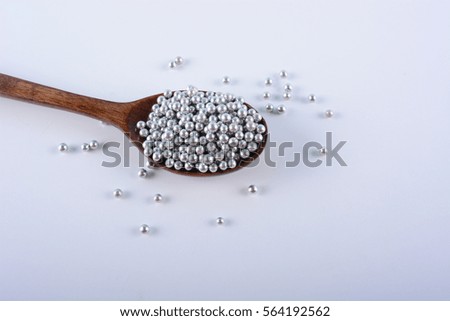 Silver Sugar Pearls on a wooden spoon. Selective Focus.